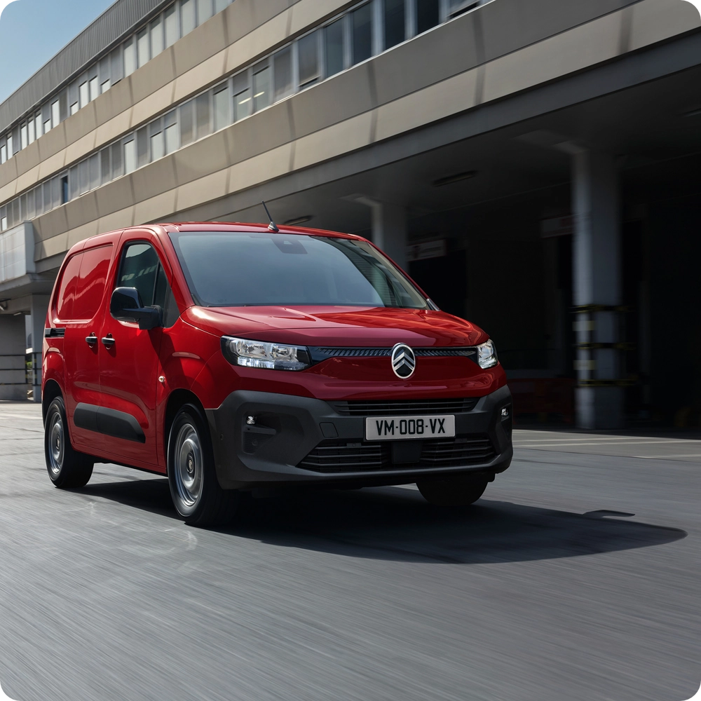 Driekwart vooraanzicht van een Citroën Berlingo Van rijdend in stedelijk verkeer, met zicht op veiligheidstechnologieën, comfort en een zelfverzekerde uitstraling.