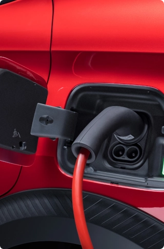 Close-up van de laadaansluiting van de Citroën ë-C3 Van aangesloten op een laadkabel, met nadruk op elektrische mobiliteit en eenvoudig opladen.