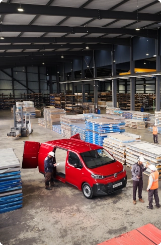 Hoog aanzicht van een rode Citroën Jumpy, geparkeerd in een industriële loods, met compacte buitenmaten, royale laadcapaciteit en professionele inzetbaarheid.
