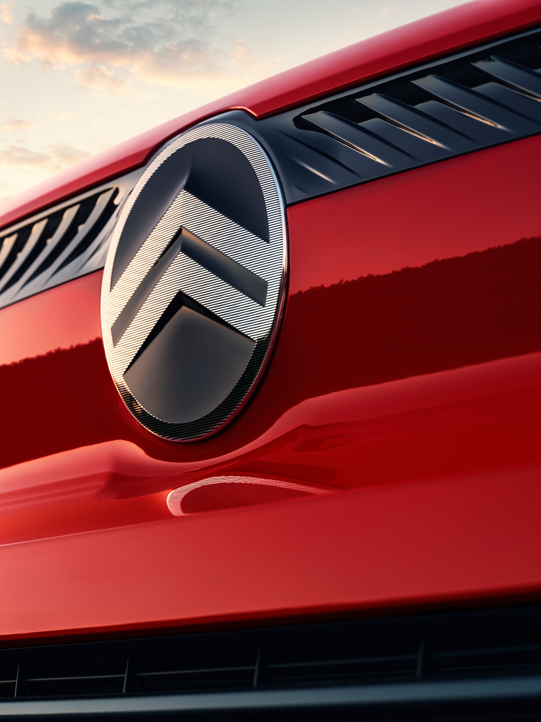Detailopname van het Citroën‑logo op een rode Citroën Jumpy, met nadruk op merkidentiteit en moderne designdetails.