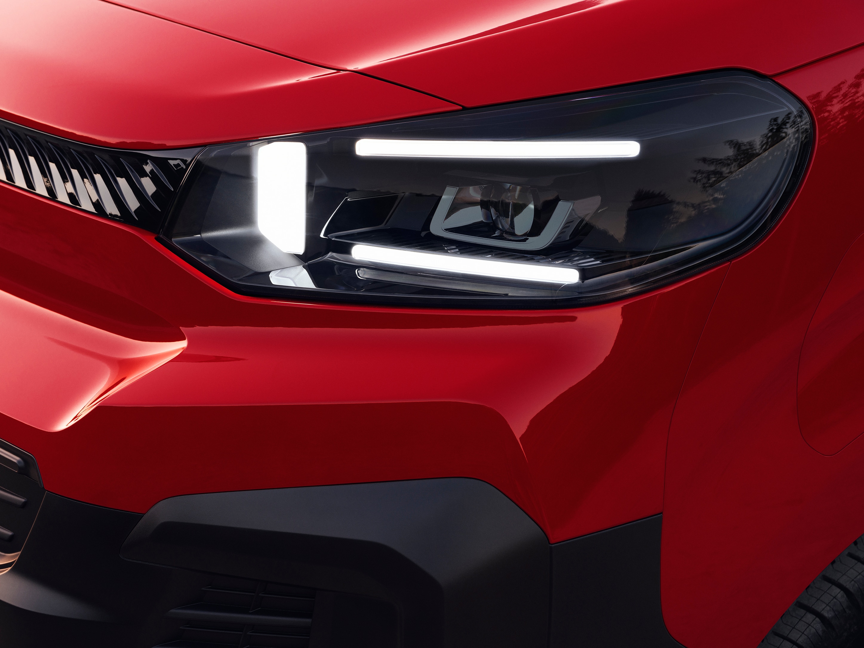 Detailopname van de voorlamp van een rode Citroën Jumpy, met modern lichtdesign en robuuste styling.