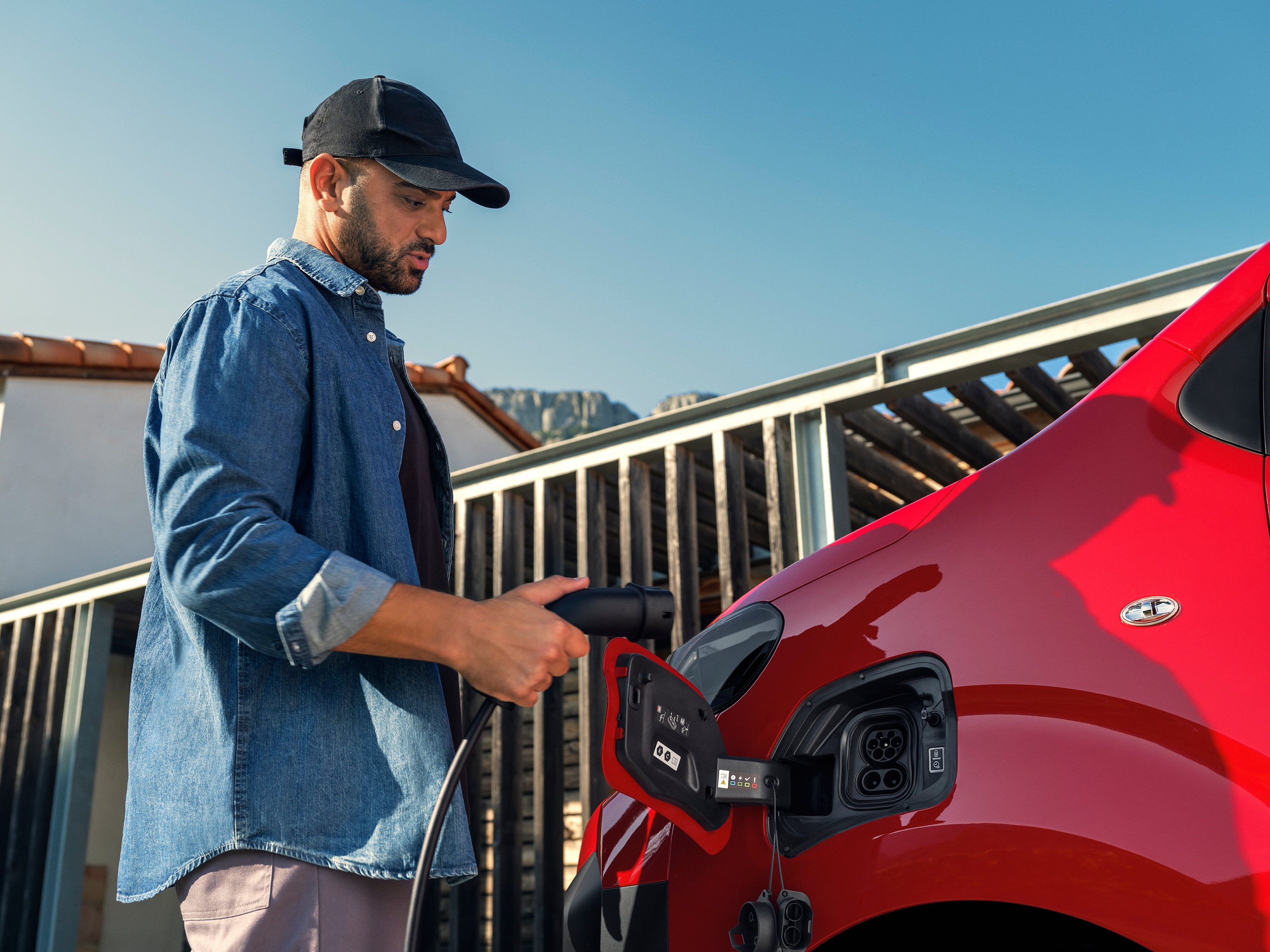 Zijaanzicht van een rode Citroën ë‑Jumpy die wordt aangesloten op een laadpunt, met nadruk op eenvoudig opladen, connected gebruik en praktische professionele mobiliteit.