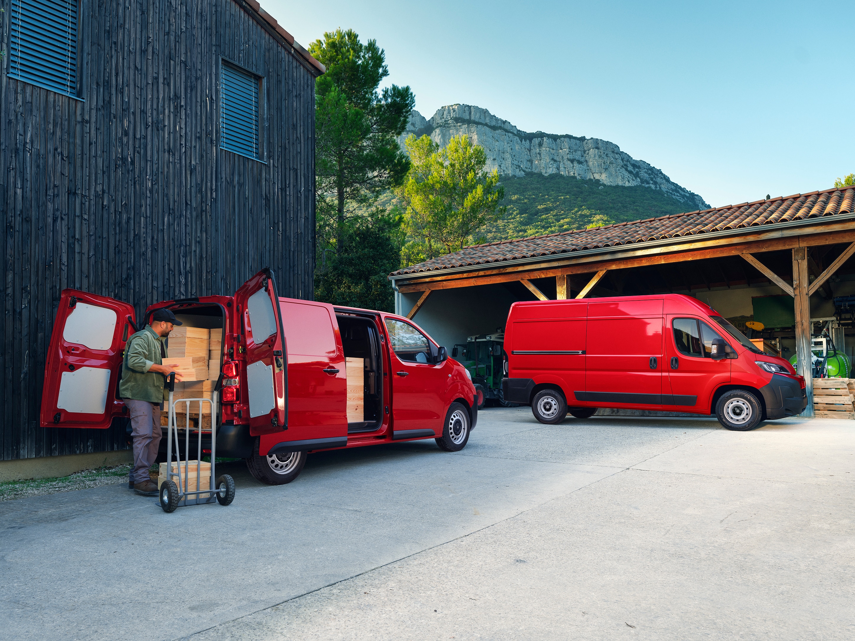 "Achteraanzicht in driekwart perspectief van twee rode Citroën Jumpy‑voertuigen geparkeerd tijdens het laden, met verschillende configuraties, een grote laadcapaciteit en geschiktheid voor dagelijkse professionele activiteiten. "