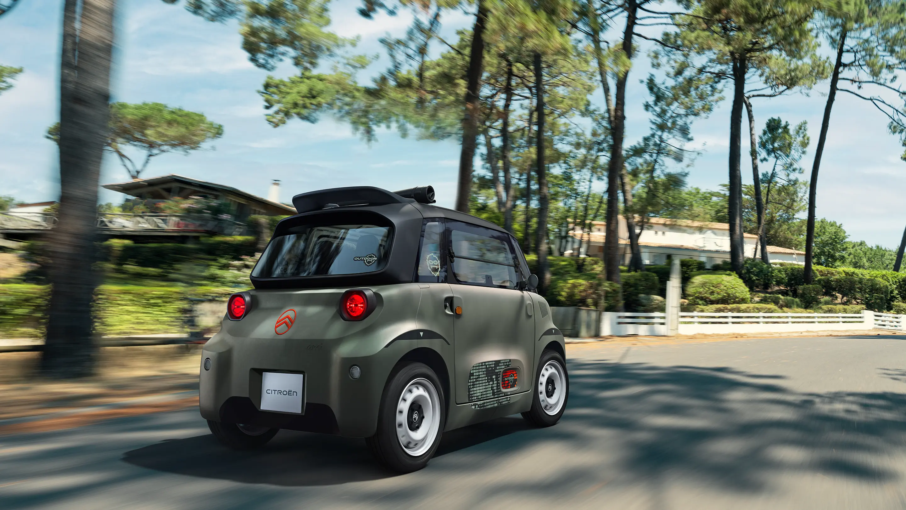 Achterkant in driekwartperspectief van de Citroën ami Outdoor met open dak: de elektrische stadsauto rijdt over boswegen