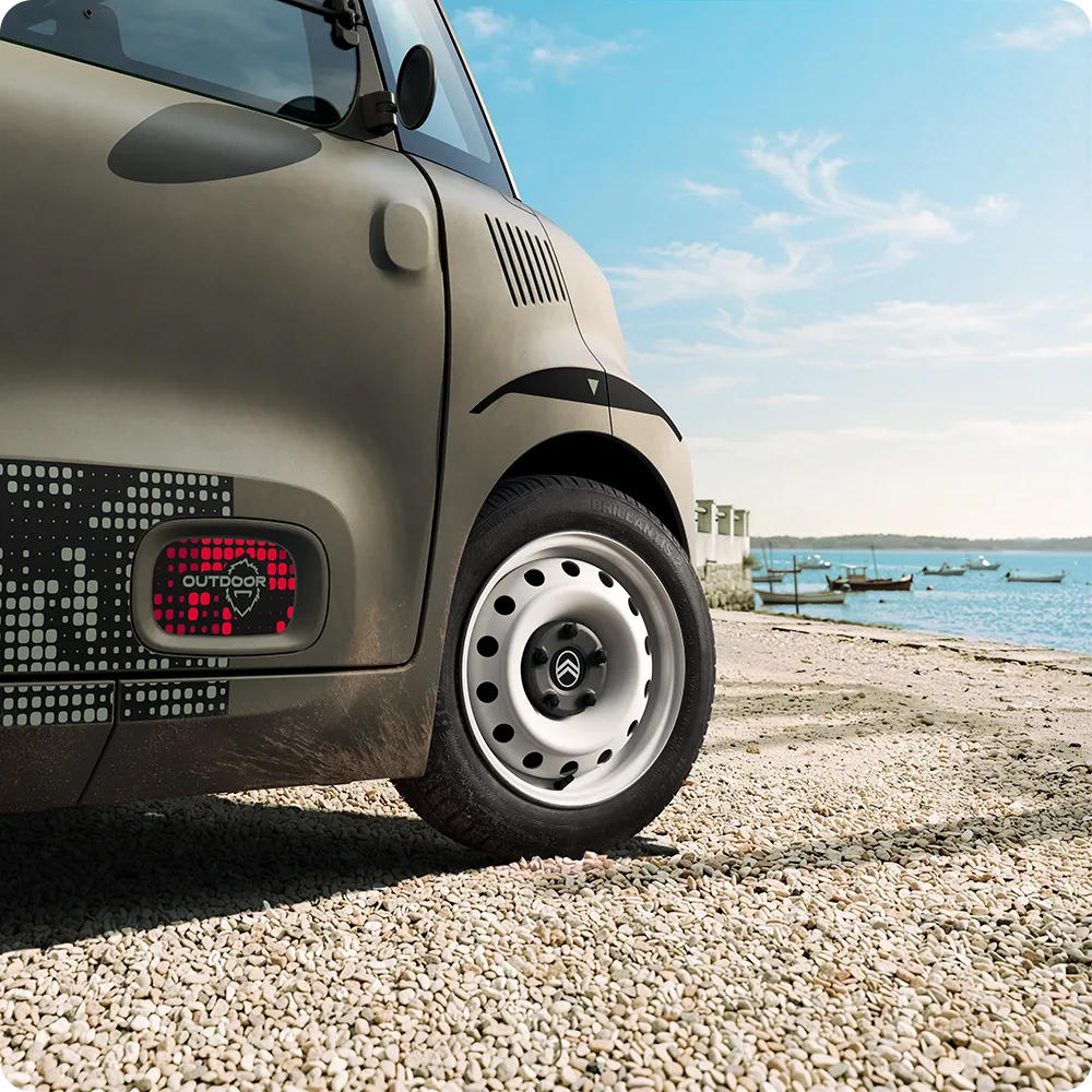 Close-up van de wielen van de Citroën ami: witte stalen velgen in Outdoor-uitvoering tonen de compacte elektrische stadsauto voor dagelijkse mobiliteit