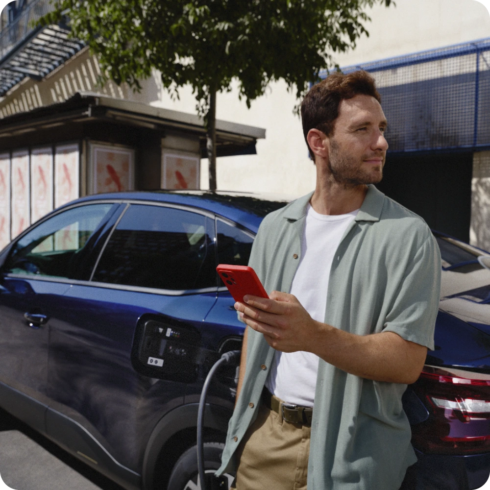 Zijaanzicht van de ë‑C4 tijdens laden terwijl trip‑planningdiensten worden gebruikt, voor eenvoudig elektrisch reizen over lange afstanden.