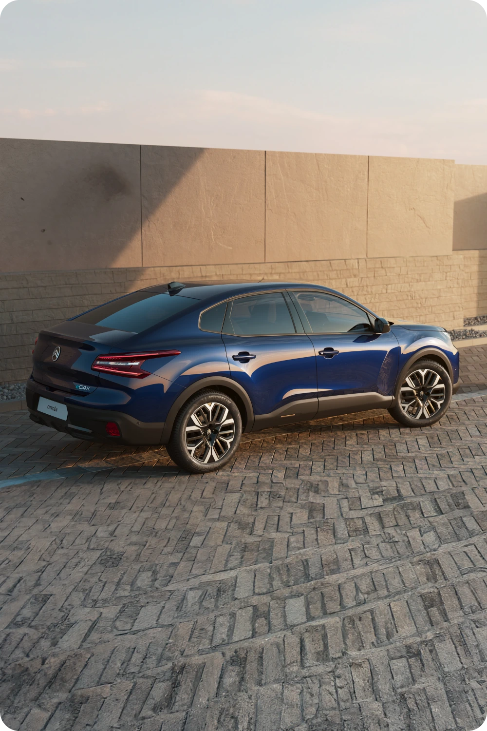 Driekwart achteraanzicht van de Citroën C4 X met slank exterieurdesign in zonlicht.