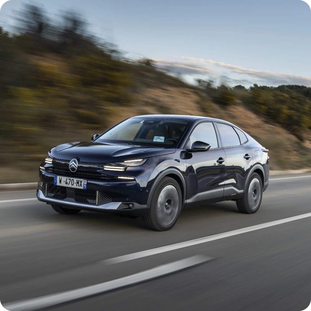 De Citroën C4 X Hybrid rijdend op een landweg, met efficiënte prestaties en een groter rijbereik.