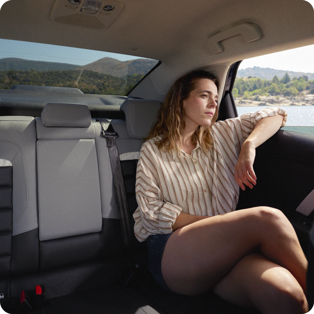 Achterbankaanzicht van de Citroën C4 X met een ontspannen passagier en een ruim, comfortabel interieur.