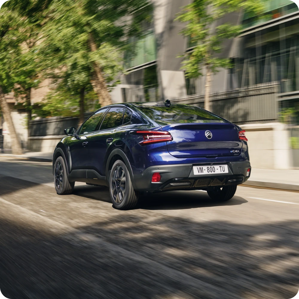 De Citroën C4 X rijdend door een stadsstraat met dynamische stijl en elektrische efficiëntie.
