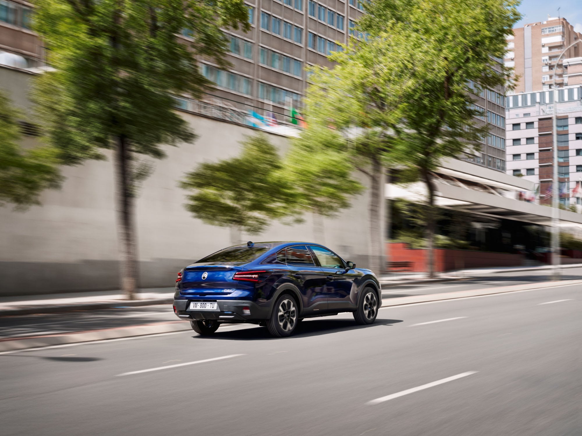 Driekwart achteraanzicht rijdend van de Citroën C4 X met moderne fastback‑stijl voor efficiënte en betaalbare mobiliteit.