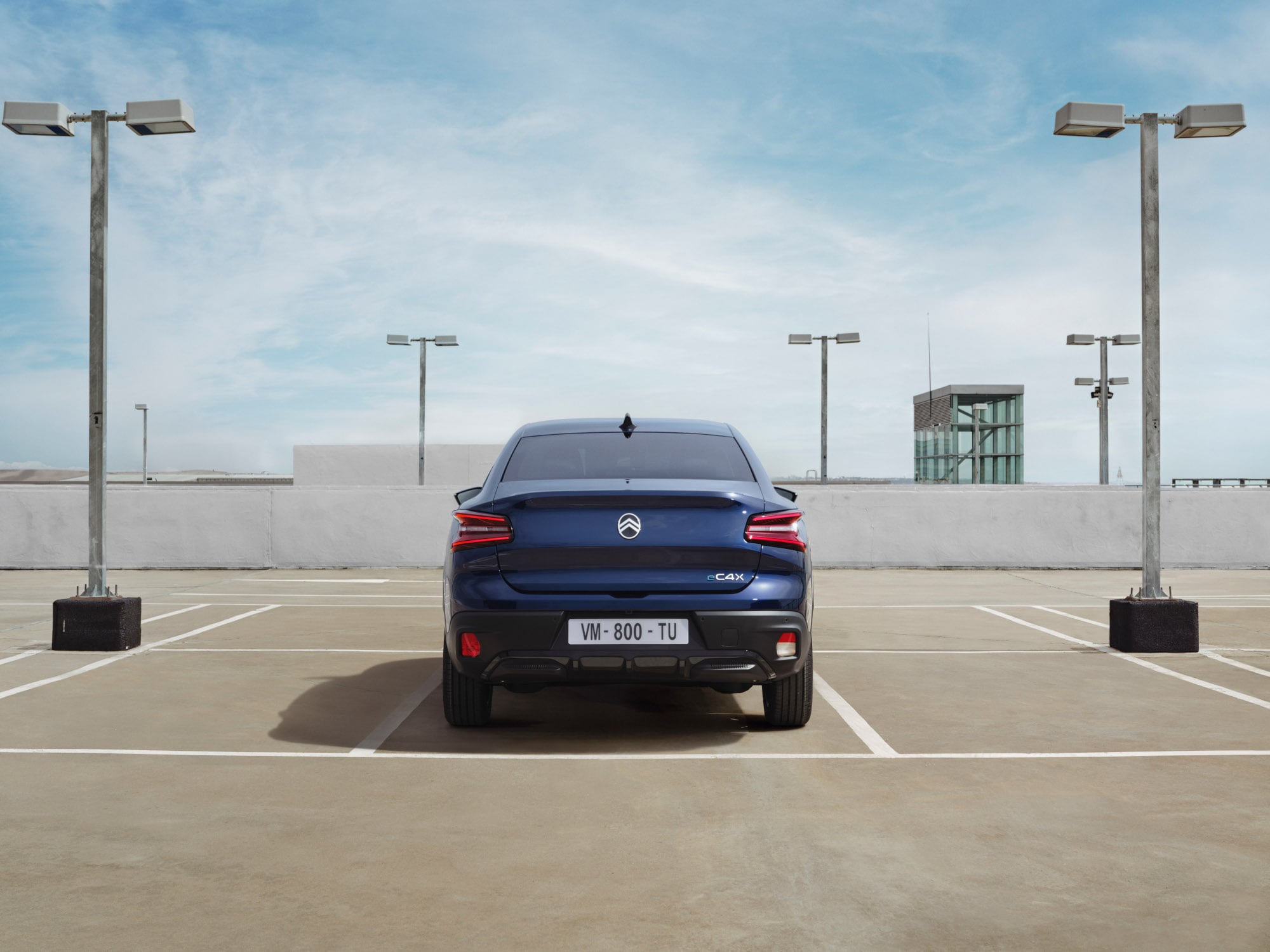 Achteraanzicht van de Citroën C4 X op een dakterrein met een onderscheidend fastback‑design voor stijlvolle en betaalbare mobiliteit.