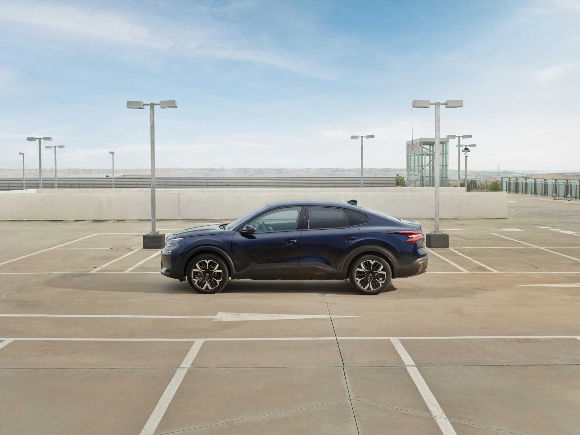 Zijaanzicht van de Citroën C4 X op een dakterrein met een slank fastback‑profiel voor efficiënte en betaalbare mobiliteit.