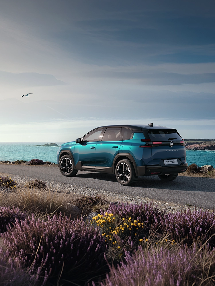 Achteraanzicht schuin van achteren van de Citroën C5 Aircross Emeraude met Light Wings LED-achterlichten tijdens een rit langs de kust