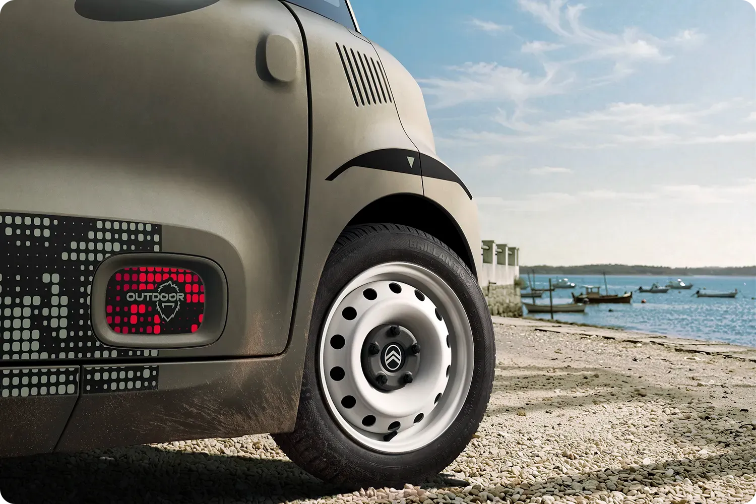 lose-up van de wielkast van de Citroën Ami Outdoor: compact, elektrisch en toegankelijk, met een innovatief design voor avonturen aan de kust.