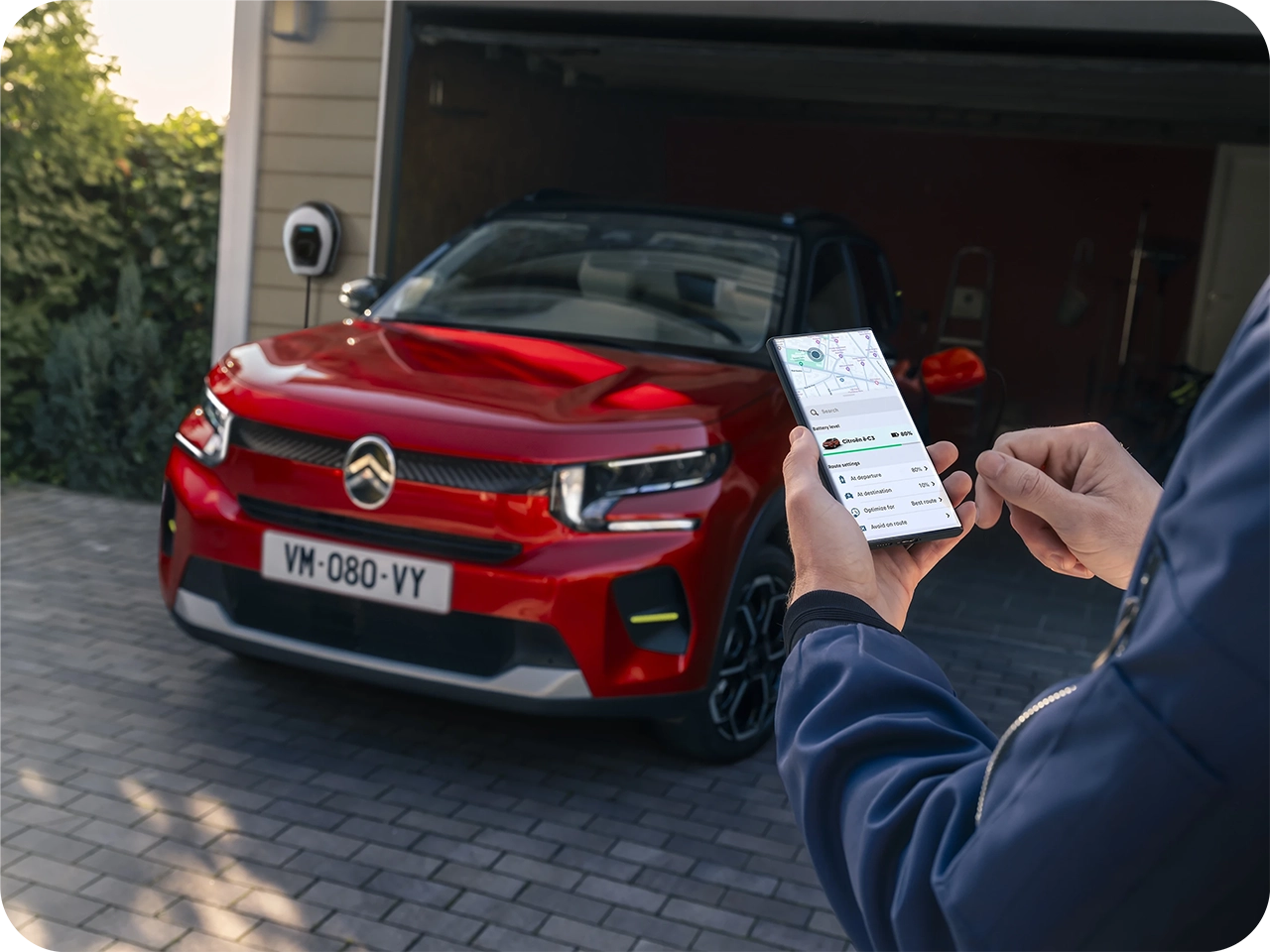 Citroën‑voertuig geparkeerd terwijl een smartphone‑app wordt gebruikt om voertuigfuncties op afstand te bedienen.