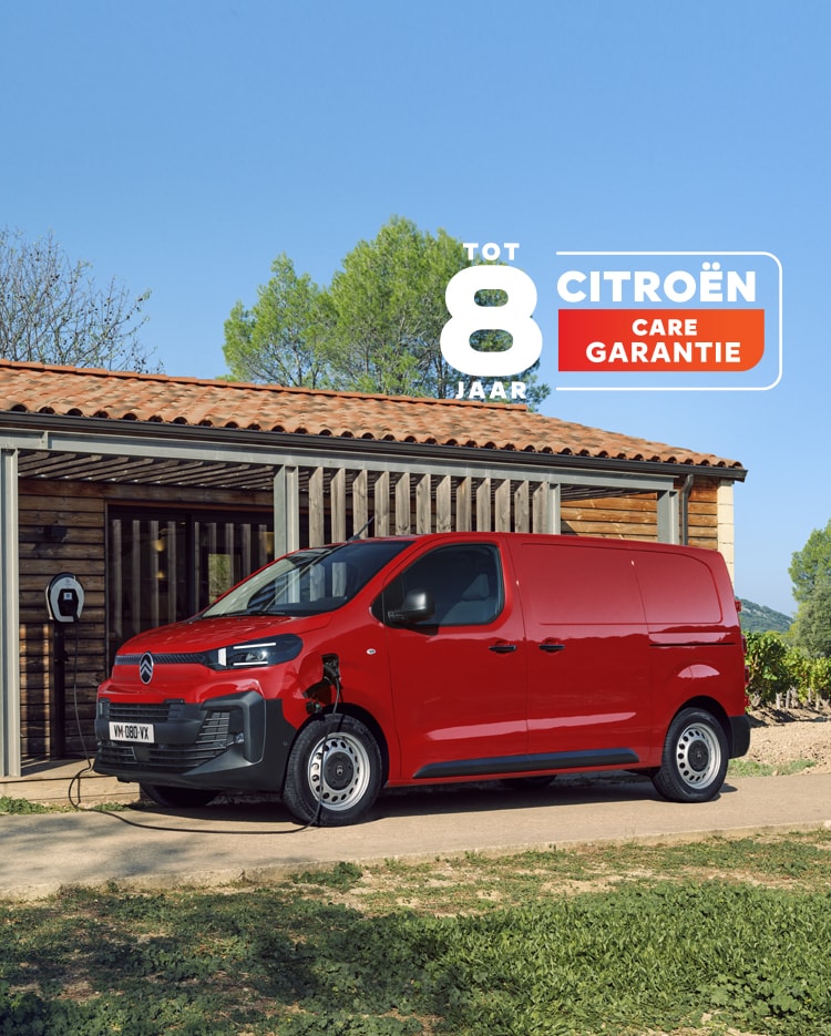 Side three‑quarter exterior view of a red Citroën ë‑Jumpy charging in front of a building, showing modern electric design, everyday practicality, connectivity and confident professional presence.